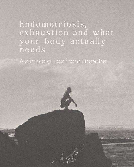 Black-and-white photo of a woman on a rock by the sea — "Endometriosis, exhaustion and what your body actually needs," a guide from Breathe.